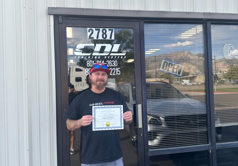 Person holding certificate outside a building.